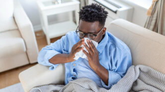 A young man experiencing flu symptoms, taking rest at home.