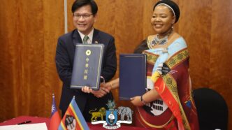 Eswatini and Taiwan officials shake hands after signing a pact to combat disinformation.