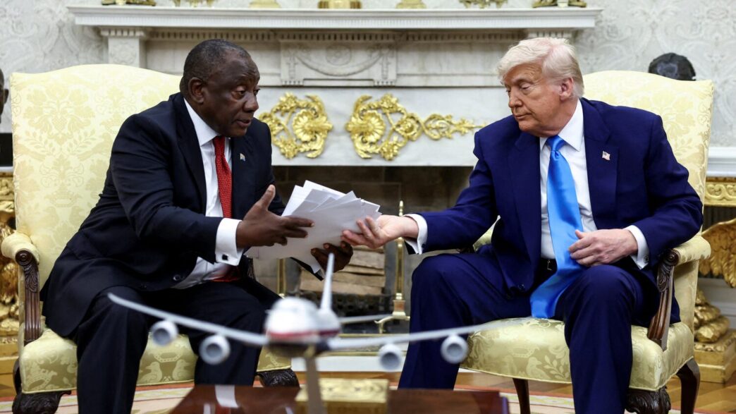 U.S. President Donald Trump hands over to South African President Cyril Ramaphosa copies of articles that he said showed white South Africans who had been killed, in the Oval Office of the White House in Washington, D.C., U.S., May 21, 2025. REUTERS/Kevin Lamarque