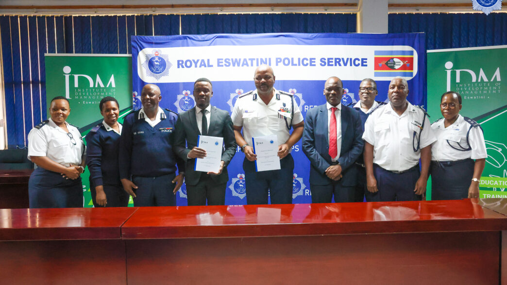 National Commissioner of Police Mr Manoma Vusi Masango and IDM Country Director Mr Karabo Baipidi display the signed Memorandum of Understanding alongside senior officials from the Royal Eswatini Police Service and the Institute of Development Management at Police Headquarters in Mbabane.