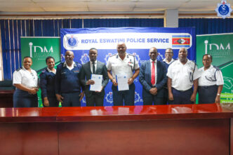 National Commissioner of Police Mr Manoma Vusi Masango and IDM Country Director Mr Karabo Baipidi display the signed Memorandum of Understanding alongside senior officials from the Royal Eswatini Police Service and the Institute of Development Management at Police Headquarters in Mbabane.