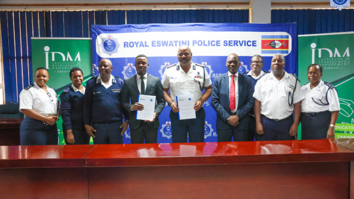 National Commissioner of Police Mr Manoma Vusi Masango and IDM Country Director Mr Karabo Baipidi display the signed Memorandum of Understanding alongside senior officials from the Royal Eswatini Police Service and the Institute of Development Management at Police Headquarters in Mbabane.