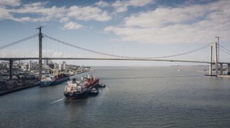 A cargo vessel navigates the waters off Maputo with the iconic Maputo-Katembe Bridge visible in the background