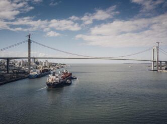 A cargo vessel navigates the waters off Maputo with the iconic Maputo-Katembe Bridge visible in the background