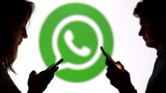 Teenagers pose for a photo while holding smartphones in front of a Whatsapp logo in this illustration taken September 11, 2025. REUTERS/Dado Ruvic/Illustration/File Photo