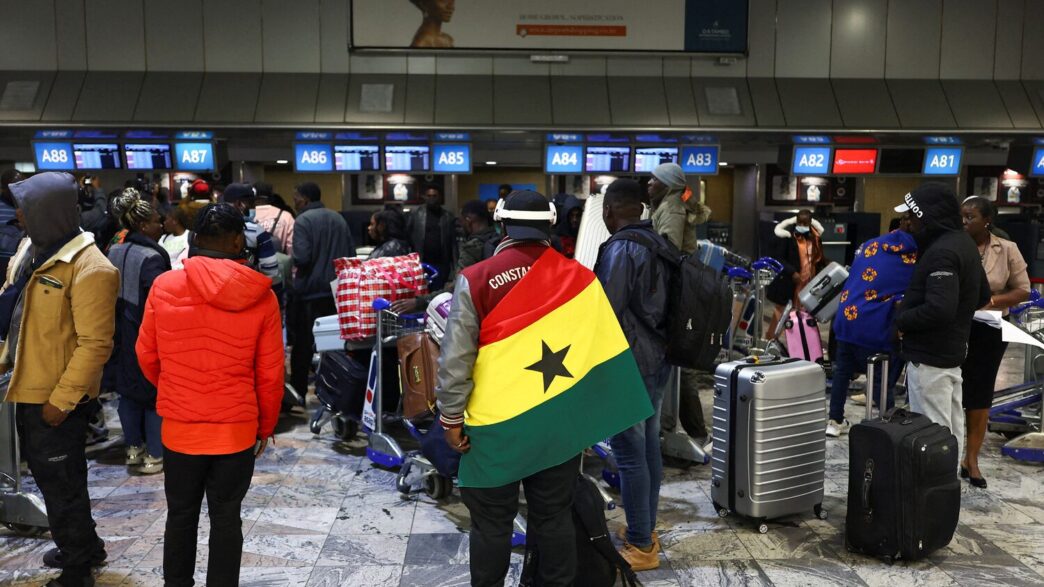 A man draped in a Ghana flag stands among other Ghanaians as Ghana repatriates hundreds of its citizens from South Africa following instances of violence against migrants from other sub-Saharan African countries, amid a wave ‌of protests against illegal immigration, at O.R. Tambo International Airport in Kempton Park, South Africa, May 27, 2026. REUTERS/Siphiwe Sibeko