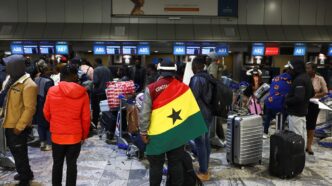 A man draped in a Ghana flag stands among other Ghanaians as Ghana repatriates hundreds of its citizens from South Africa following instances of violence against migrants from other sub-Saharan African countries, amid a wave ‌of protests against illegal immigration, at O.R. Tambo International Airport in Kempton Park, South Africa, May 27, 2026. REUTERS/Siphiwe Sibeko