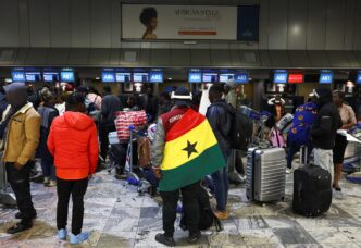 A man draped in a Ghana flag stands among other Ghanaians as Ghana repatriates hundreds of its citizens from South Africa following instances of violence against migrants from other sub-Saharan African countries, amid a wave ‌of protests against illegal immigration, at O.R. Tambo International Airport in Kempton Park, South Africa, May 27, 2026. REUTERS/Siphiwe Sibeko