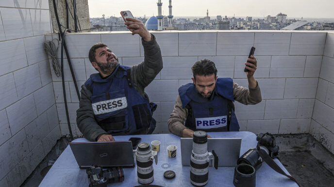 Palestinian journalists attempt to connect to the internet using their phones in Rafah on the southern Gaza Strip on December 27, 2023. Said Khatib / AFP