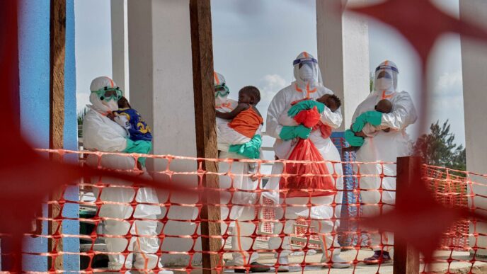 Congolese medical workers dressed in personal protective equipment (PPE) carry children tested and cleared off from Ebola from Saint Nicholas orphanage, at the Centre Medical Evangelique (CME) within the secured Ebola response zone, as aid agencies intensify efforts to contain the Ebola outbreak involving the Bundibugyo strain, in Hoho commune of Bunia town, Ituri province, Democratic Republic.