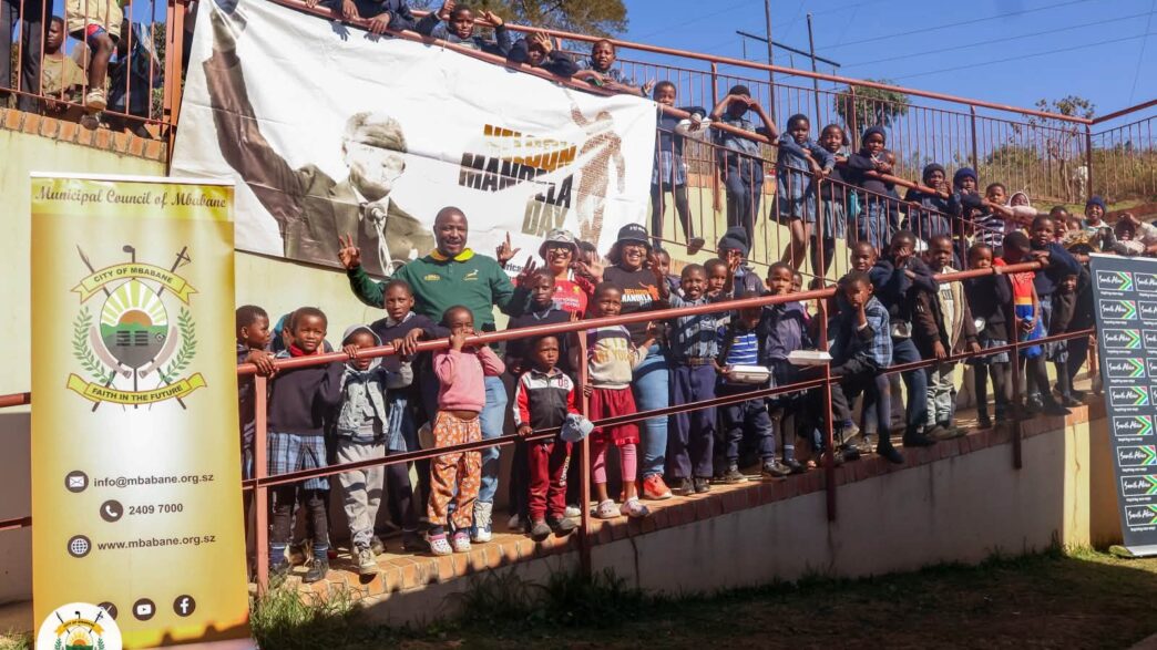 Mbabane City Mayor Mr. Thulani Mkhonto and Chief Executive Officer Ms. Gciniwe Fakudze pose for a group photo with some of the children they served meals to at the Sidwashini Social Centre. Photo by Municipal Council of Mbabane